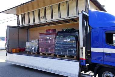 Çeşitli renkli mallarla dolu paletleri boşaltan kamyon