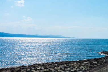 Güzel sahil manzarası, ufuktaki su ve tepeler.         
