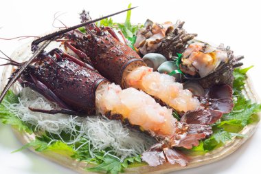 Istakoz ve diğer deniz ürünleriyle dolu bir tabak yemek.