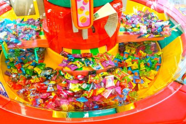 Parlak oyun makinesini dolduran renkli paketlenmiş şekerler