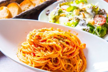 Domatesli spagetti ve rendelenmiş peynir kasede.