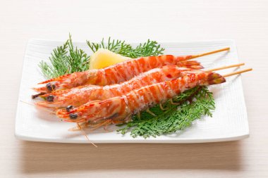 Limonlu ızgara karides ve beyaz tabakta yeşil dal.