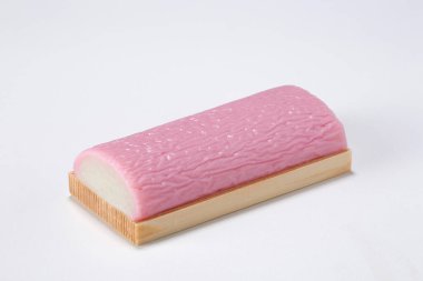 Pink kamaboko fish cake resting on wooden board