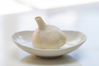 Beyaz bir masada bir kase sarımsak.