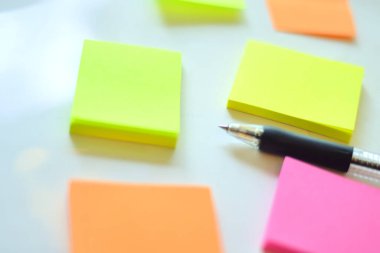 Beyaz masa arkaplanında kalem olan renkli yapışkan notlar