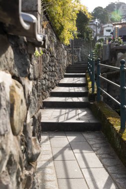 Güneş ışığı, taştan patika boyunca açık havada adımlarla gölgeler bırakıyor.