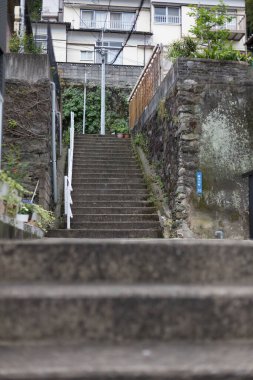 Beton merdivenler taş duvarlar arasından konut binalarına doğru yükseliyor.