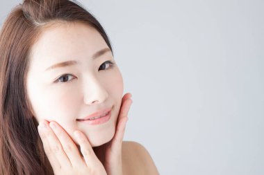 Güzel gülümseyen Asyalı kadın yüzüne dokunuyor