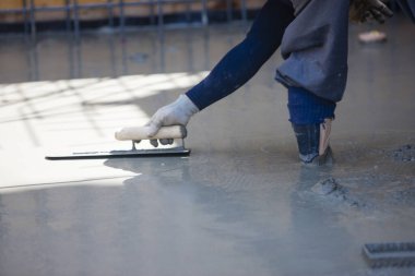 İnşaat alanındaki çimentoyu düzleştirmek için spatula kullanan işçiler