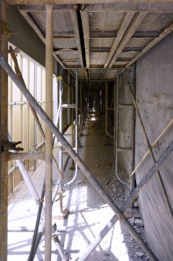 Bitmemiş inşaat koridorunu çevreleyen metal iskeleler.