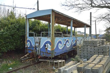 Terk edilmiş mavi lunapark treni beton blokların arasında duruyor.