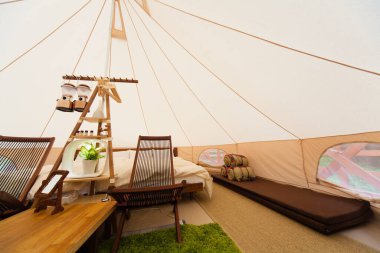 İçinde yatak ve sandalyeler olan büyük beyaz bir çadır. 