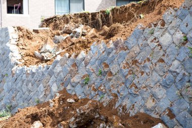 Yerleşim yerinin yakınındaki toprak erozyonunu ortaya çıkaran istinat duvarı çökmüş.