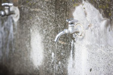 Kirli duvarlara su dökülen musluk. 