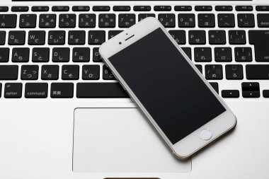 Akıllı telefonlu modern laptop ve beyaz masadaki boş ekran, üst görünüm