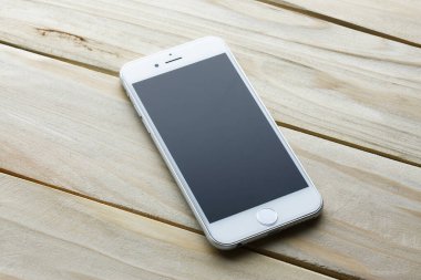 Ahşap arka planda boş ekranı olan modern akıllı telefon, üst görünüm