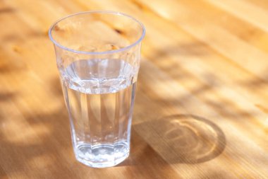 Ahşap zemin üzerinde su bardağının yakın görüntüsü.      