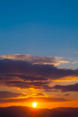 Gökyüzünde dramatik bulutlarla dağların üzerinde renkli gün doğumu manzarası