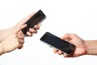 Beyaz arka planda izole edilmiş akıllı telefonları tutan iki el. 