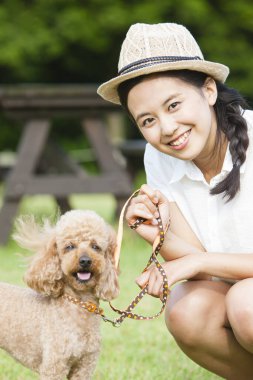 Dışarıda köpek yavrusuyla dolaşan genç Asyalı kadın.