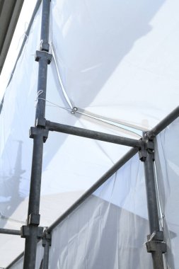 Açık havada şeffaf plastiği destekleyen yapı iskelesi