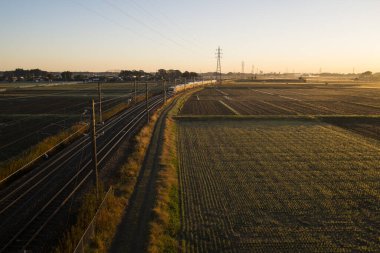Demiryolu rayları ve yeşil tarlalar üzerinde gün doğumu