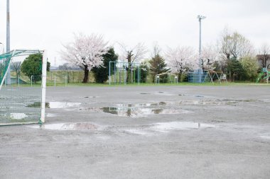 Şehirde yağmurdan sonra birikintileri olan boş bir futbol sahası