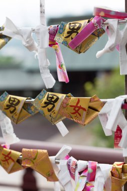 Açık havada beyaz kurdeleler arasında asılı renkli kağıt servetler