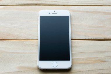 Ahşap arka planda beyaz bir ekranı olan akıllı telefon. Yeni teknoloji kavramı, modern teknolojiler..