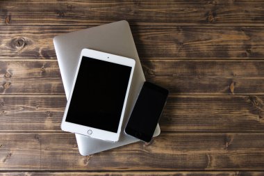 Modern akıllı telefon, dizüstü bilgisayar ve tablet bilgisayar ahşap masanın üzerinde.