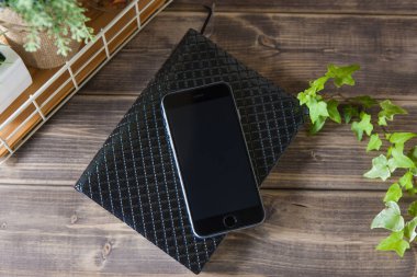 Smartphone ve ahşap masa üstünde defter.