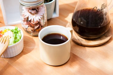 Kahveli kavanoz ve fincan, tahtadan masada kahvaltı.