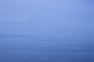 Karanlık gökyüzü, bulutlar, deniz ve dağlarla sabah