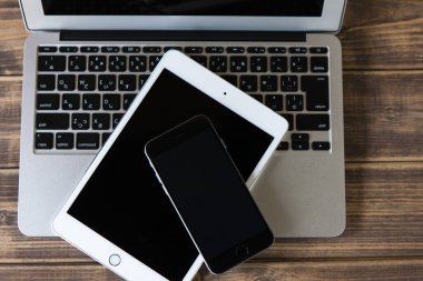 Siyah ekranlı modern bir tabletin üst görüntüsü ve boş ekranlı bir akıllı telefon