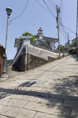 Dik taşlarla döşenmiş cadde geleneksel beyaz binanın önünden yükseliyor.