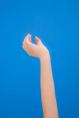 Mavi arka planda manikürlü bir kadın eli..