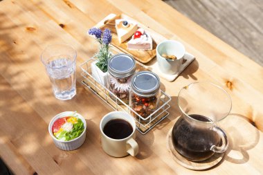 Cam kavanozlu tepsi, ahşap masa, kahve, salata ve kek.