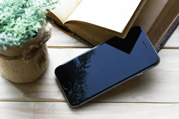 black mobile phone with blank screen on wooden desk
