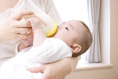 Anne bebeği sütle besliyor.