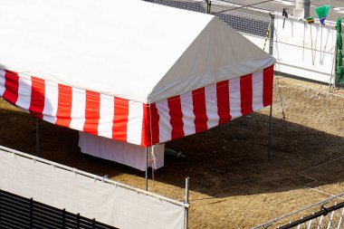 Çizgili kırmızı beyaz çadır çıplak toprakta duruyordu.