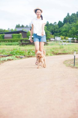 Dışarıda köpek yavrusuyla dolaşan genç Asyalı kadın.