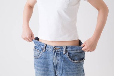 Kot pantolon deneyen Asyalı genç, zayıf kadın.