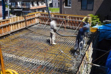 İnşaat alanında yer yapmak için çimento döken işçiler 