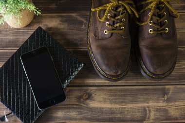 Ahşap bir masada deri çizmeleri olan modern akıllı telefon..