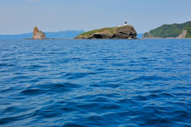 Denizdeki kayaların üzerindeki deniz feneri