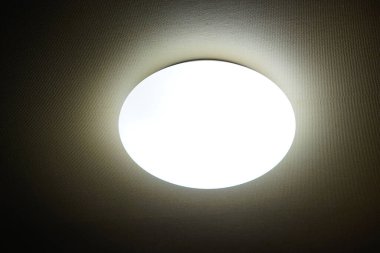 Parlak tavan ışığı koyu dokulu tavan yüzeyini aydınlatıyor