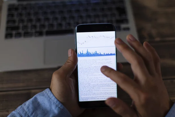 商人使用智能手机 手机屏幕上有金融统计图 — 图库照片