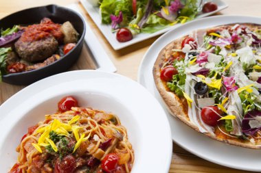 Masada çeşitli yemekler, İtalyan pizzası, spagetti bolonez, salata ve sebzeli haşlanmış et.