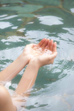 Japon onsen sıcak bahar banyosunda dinlenen bir kadının kırpılmış fotoğrafı.