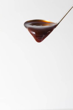 thick dark sauce flowing from ladle on a white background clipart